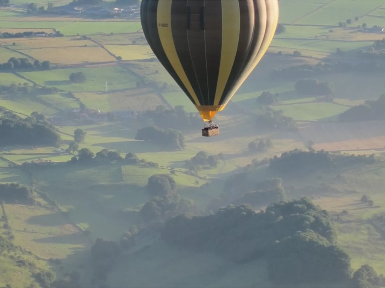 A hot air balloon flies over a scenic landscape.