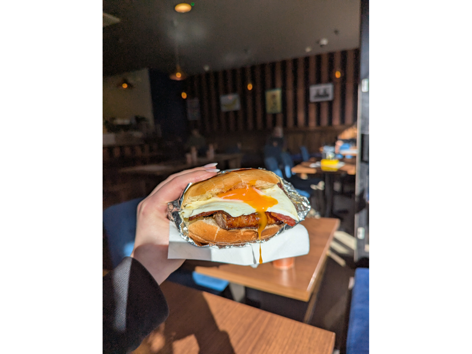 A delicious sausage and egg sandwich being held aloft in the Copper Pot Café.