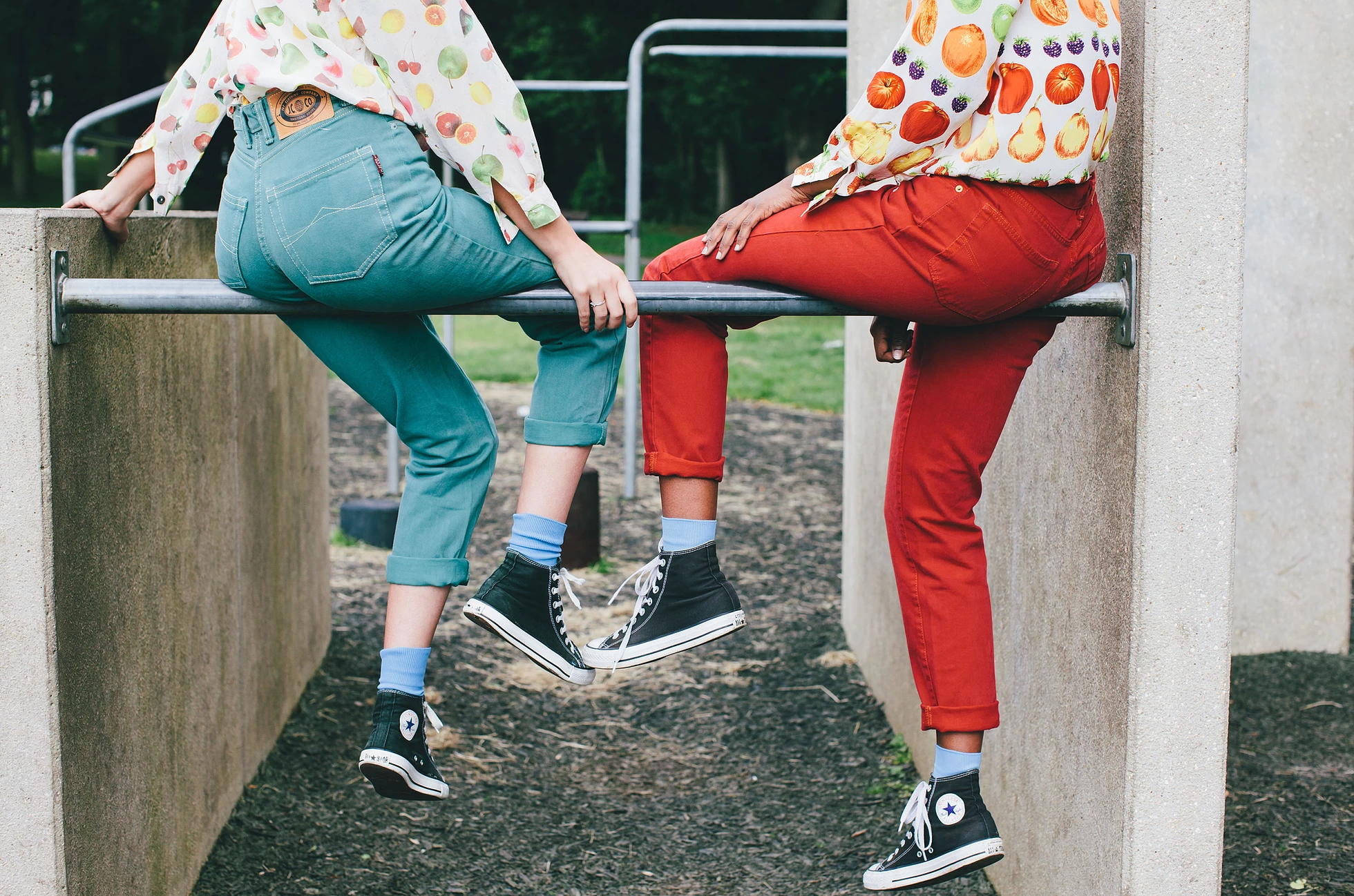 Two people sat om a metal bar between two concrete blocks.