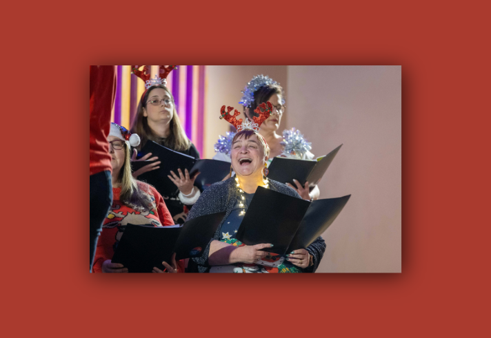 A choir, dressed in festive Christmas themed attire, performing.