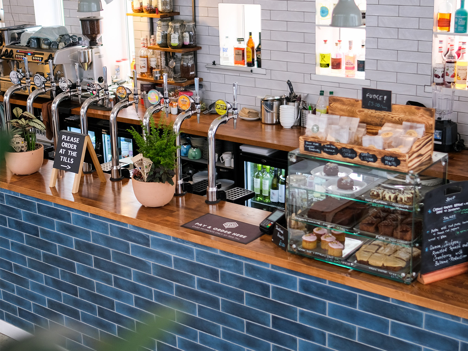 The blue-tilled counter at The Treehouse Cafe.  There are lots of drinks, and a display case filled with treats and pastries.