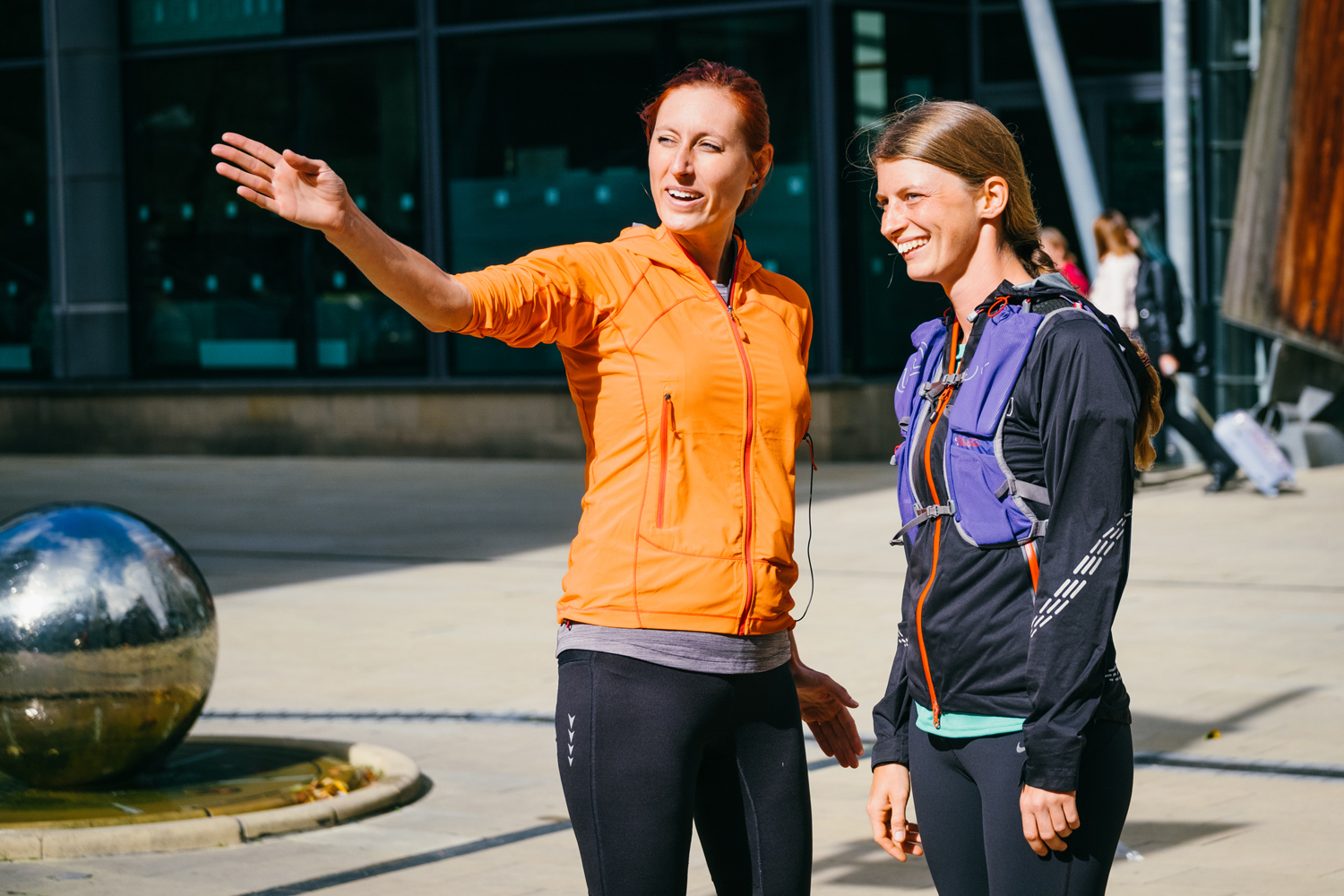 Two women in a running club, one woman is directing the other where to go.
