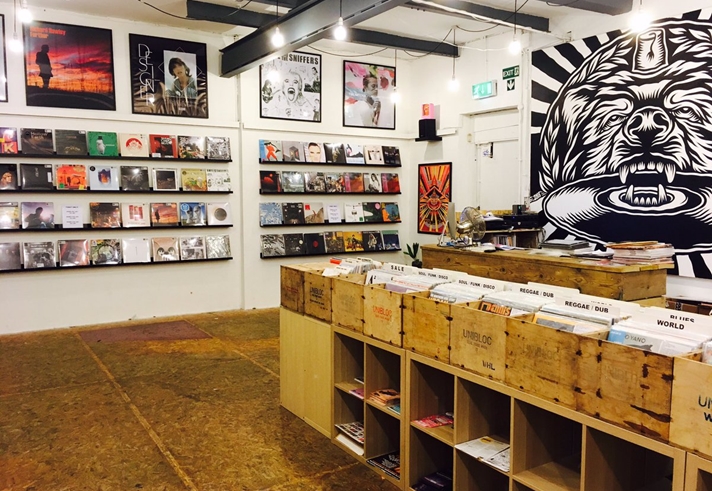 Inside Bear Tree Record, there are rows of wooden units holding records. On the walls new releases are displayed. One section of the wall has a floor to ceiling mural of the Bear Tree Records logo, painted by Sheffield artist Tom J Newell.
