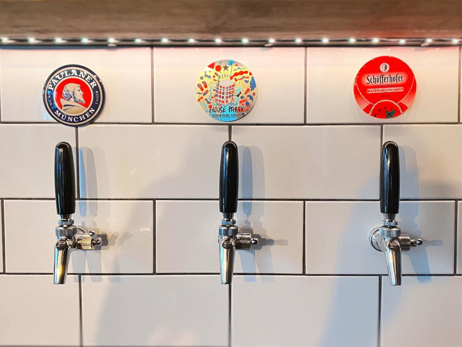 Beer taps set into a white tiled wall at Hymn To Ninkasi