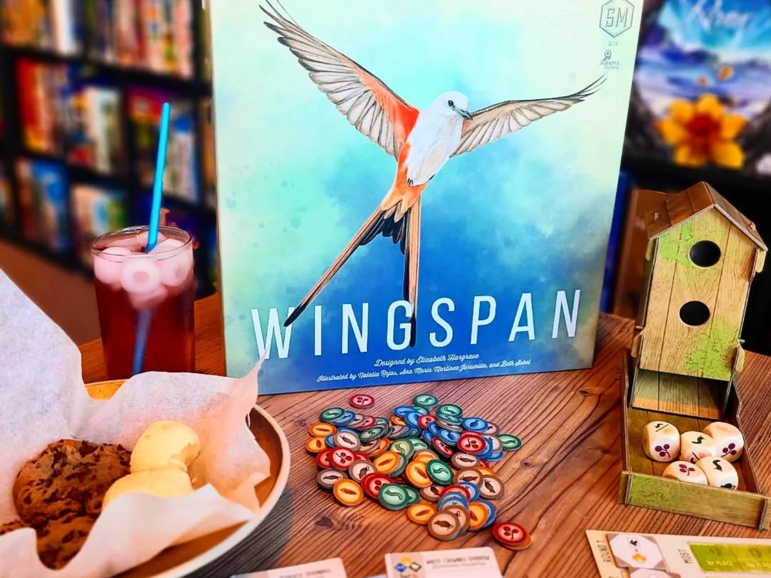 A table at The Dice Box Sheffield, with cakes and a drink and a game called Wingspan.