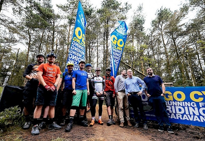 The MTB community stood together as a group in a forest.
