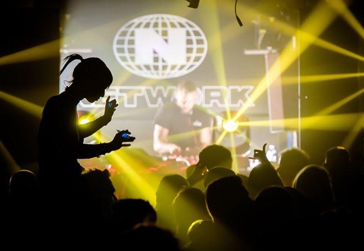 A nightclub full of people dancing, lit by yellow lighting.