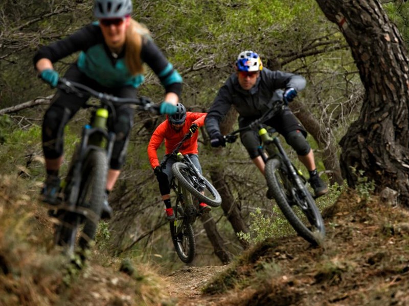 Three people riding mountain bikes at speed through Fox Valley.