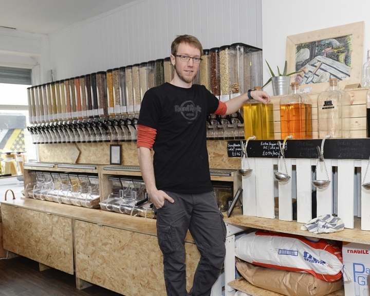 The owner of Bare Alternative standing in his shop in front of rows of produce.