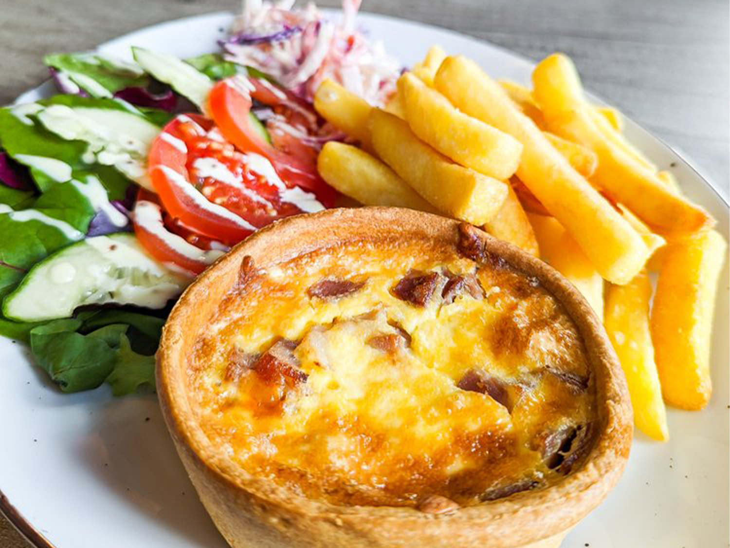 Quiche, chips and salad on a plate.