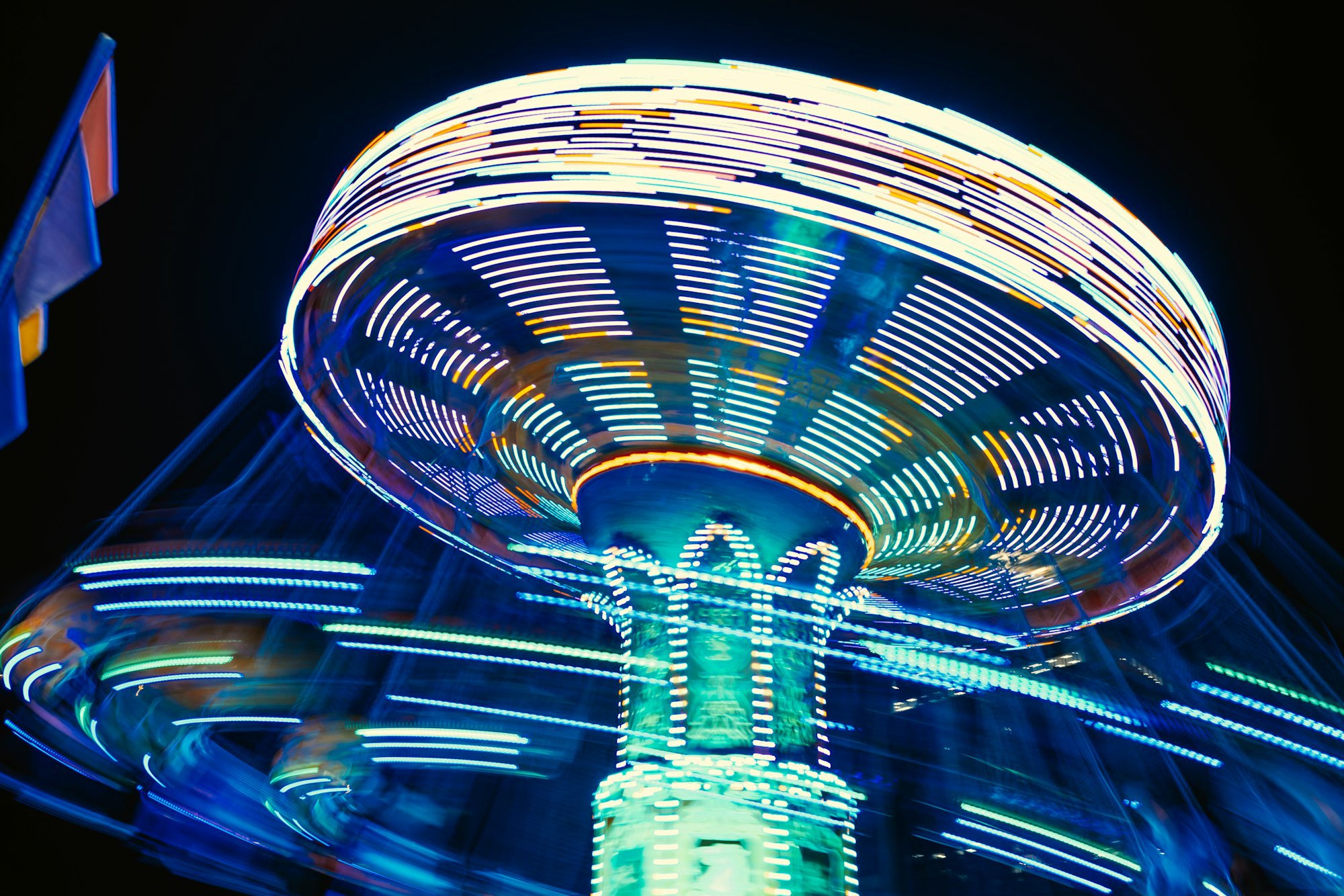 A fairground ride whizzing round as it's lit up in icy blue tones at night