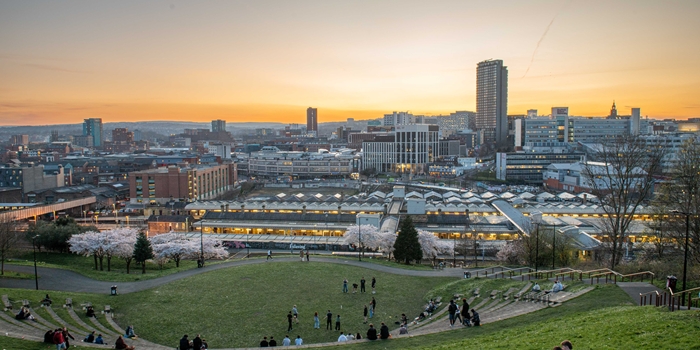A striking cityscape view of Sheffield at dusk taken from South Street Park amphitheatre during springtime with blossom on the trees