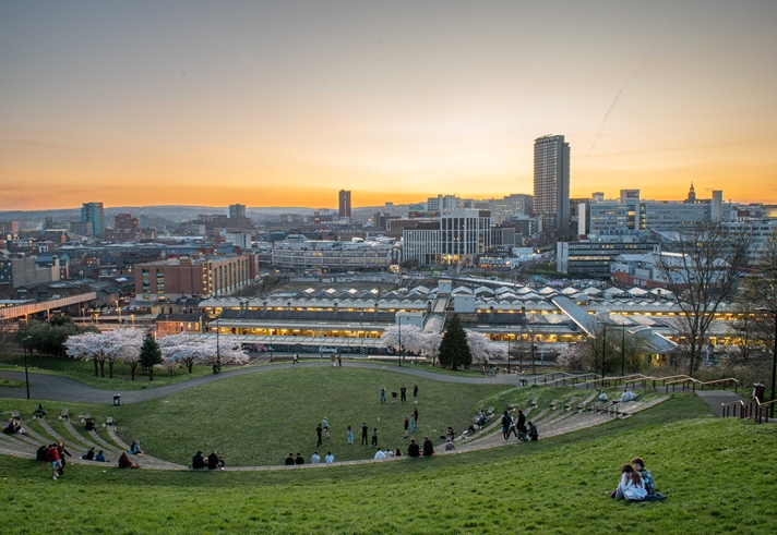 A striking cityscape view of Sheffield at dusk taken from South Street Park amphitheatre during springtime with blossom on the trees