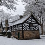 The Bishop's House in the snow. The bottom half of the building is stone and the top half is black and white timbers.