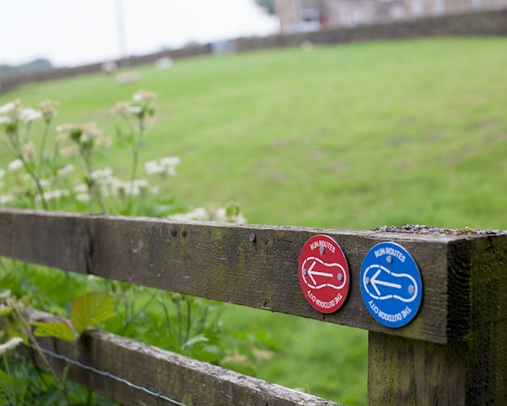 Blue and red signs on a wooden gate directing people to the Bradfield to DamFlask Reservoir run route.