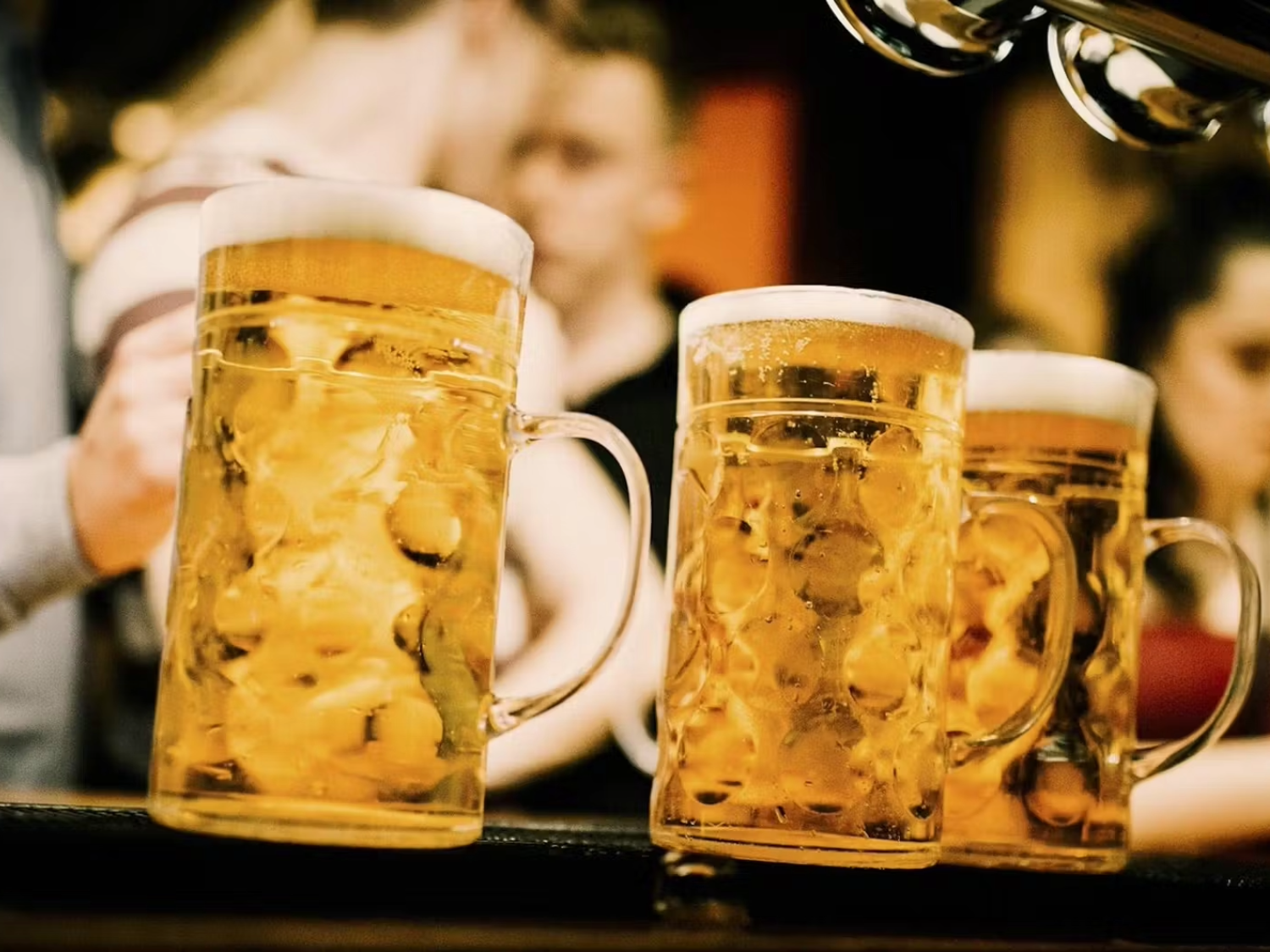 Three steins of beer on a bar top.
