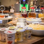 Assorted breakfast choices including cereals, fruit, pastries, and beverages arranged on a table.