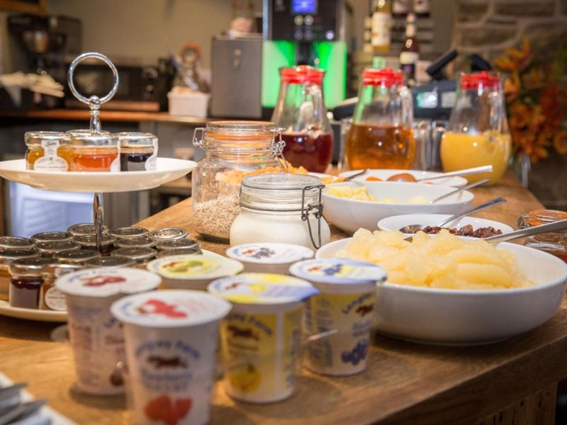 Assorted breakfast choices including cereals, fruit, pastries, and beverages arranged on a table.