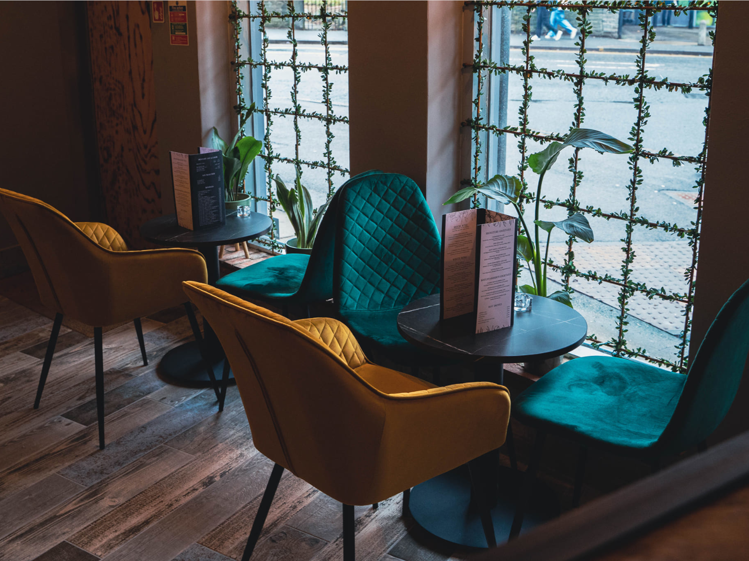 Beautifully upholstered chairs with tables by the window at Boulevardier