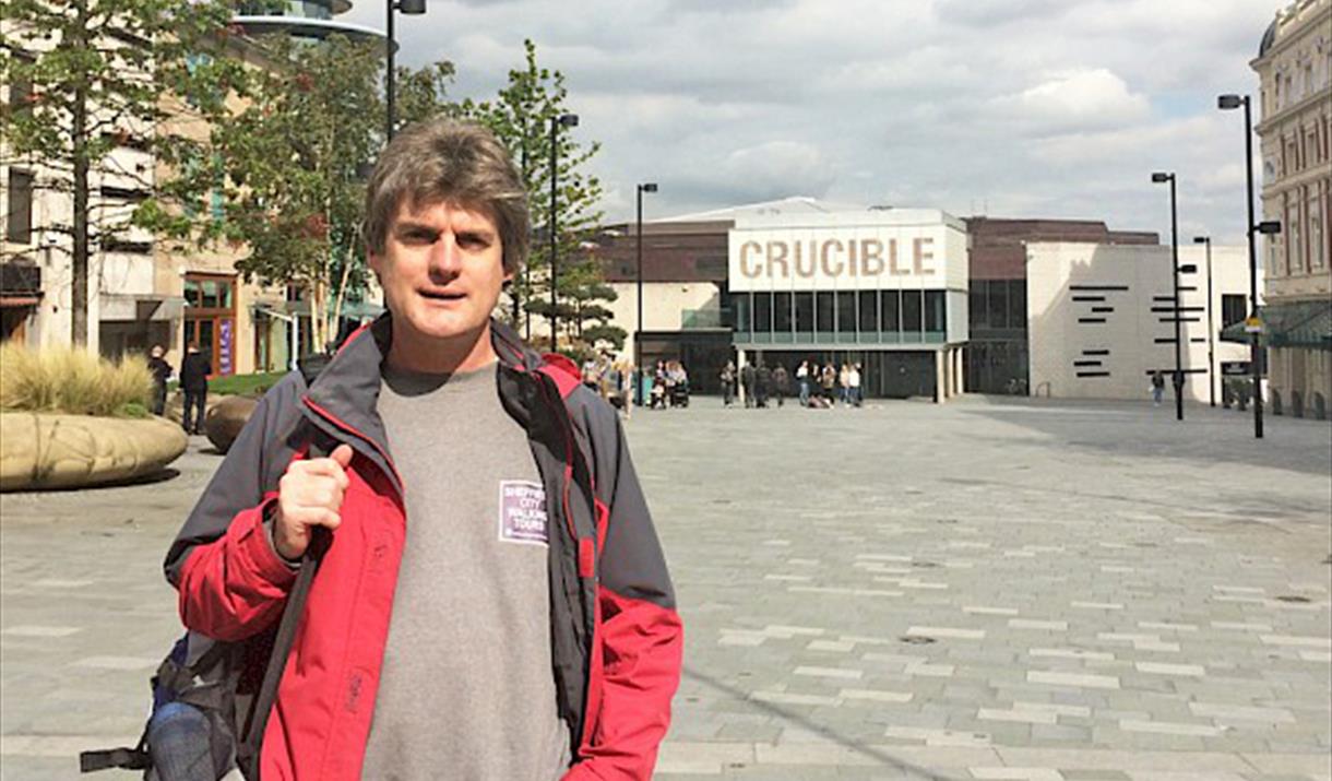 Marcus Newton, the guide for Sheffield City Walking, standing in Tudor Square on a bright, sunny day.
