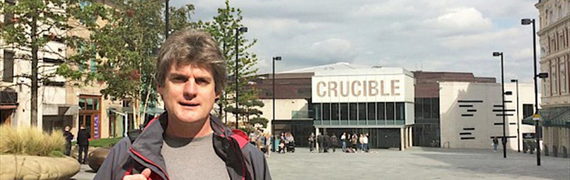 Marcus Newton, the guide for Sheffield City Walking, standing in Tudor Square on a bright, sunny day.