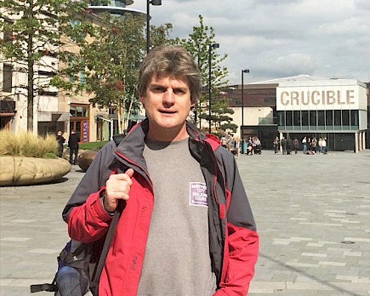 Marcus Newton, the guide for Sheffield City Walking, standing in Tudor Square on a bright, sunny day.