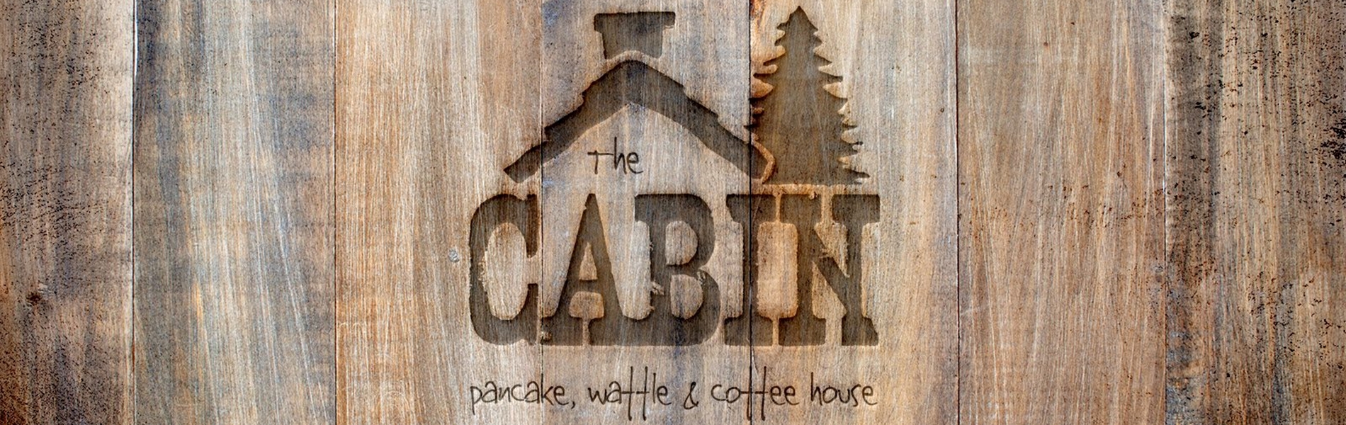 The Cabin logo on a wooden wall.