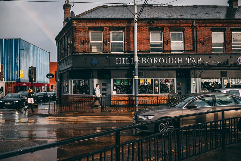 Tram tracks and The Hillsborough Tap, with rainbow in the sky in the background.