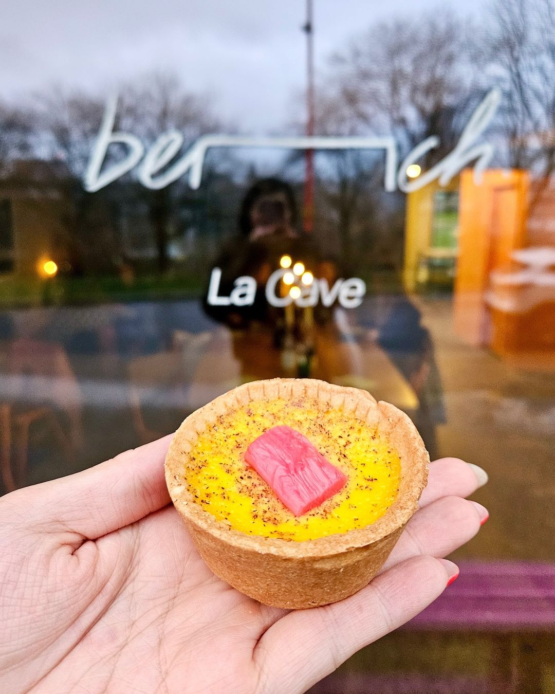 A hand holding an individual tart.