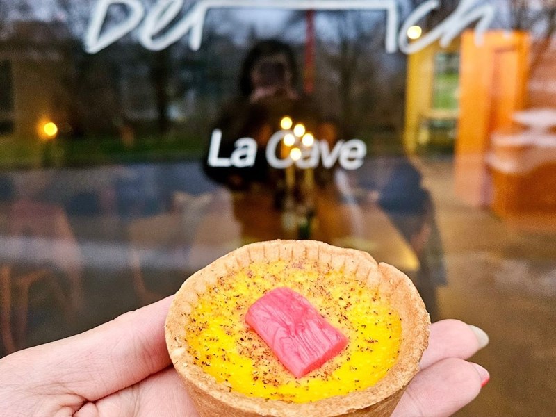 A hand holding an individual tart.