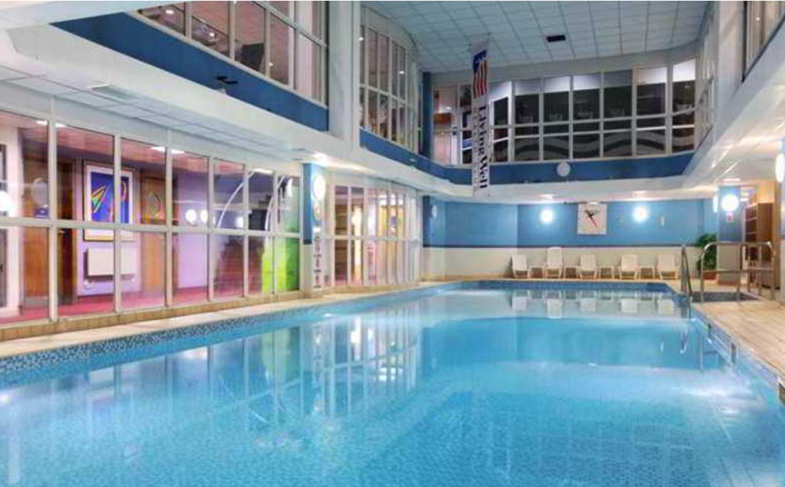 Large swimming pool with ambient lighting inside a leisure centre.
