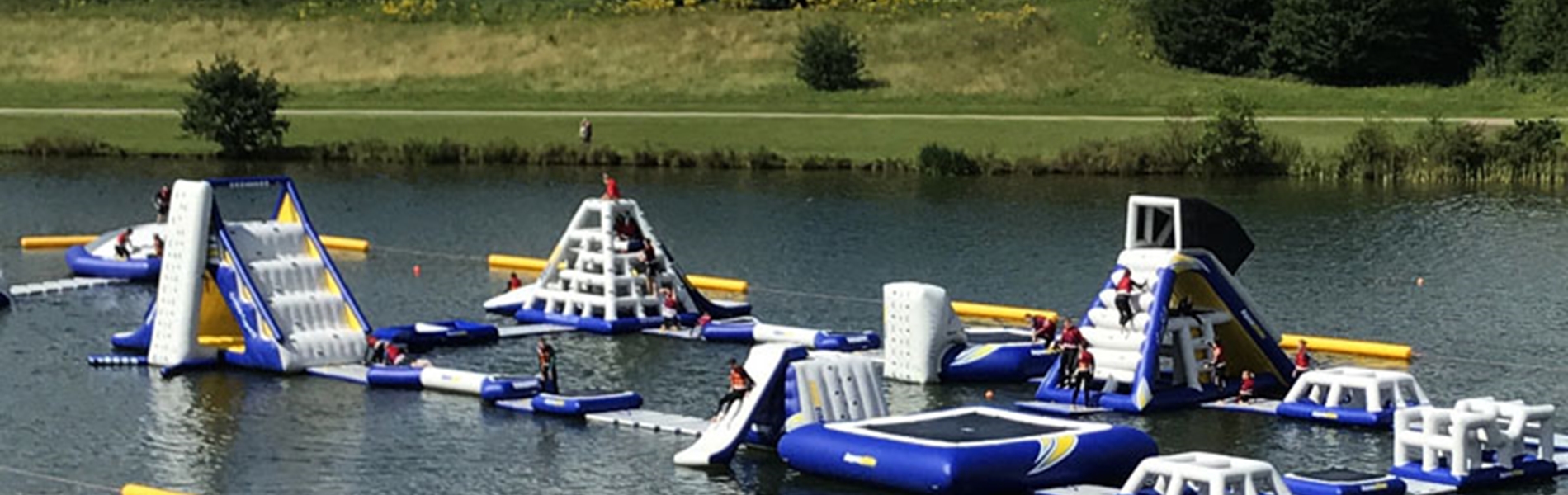 A variety of inflatable obstacles are floating on a lake.