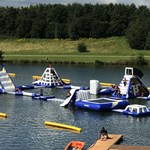 A variety of inflatable obstacles are floating on a lake.