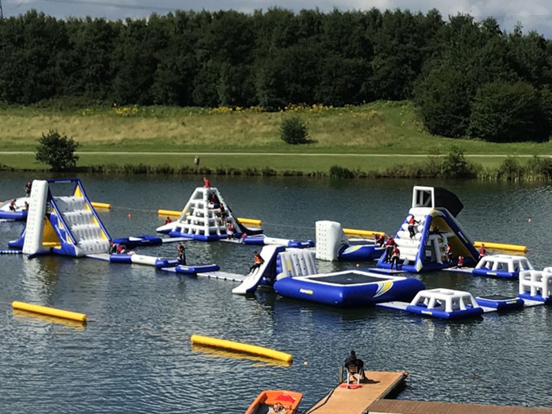 A variety of inflatable obstacles are floating on a lake.