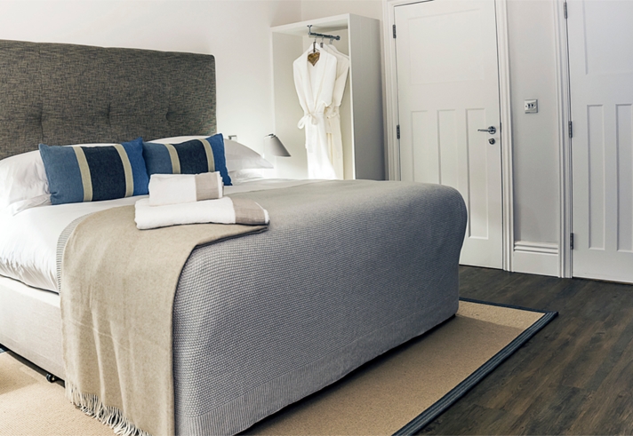 Beautiful double bed with soft furnishings in light, neutral colors and decorative cushions.