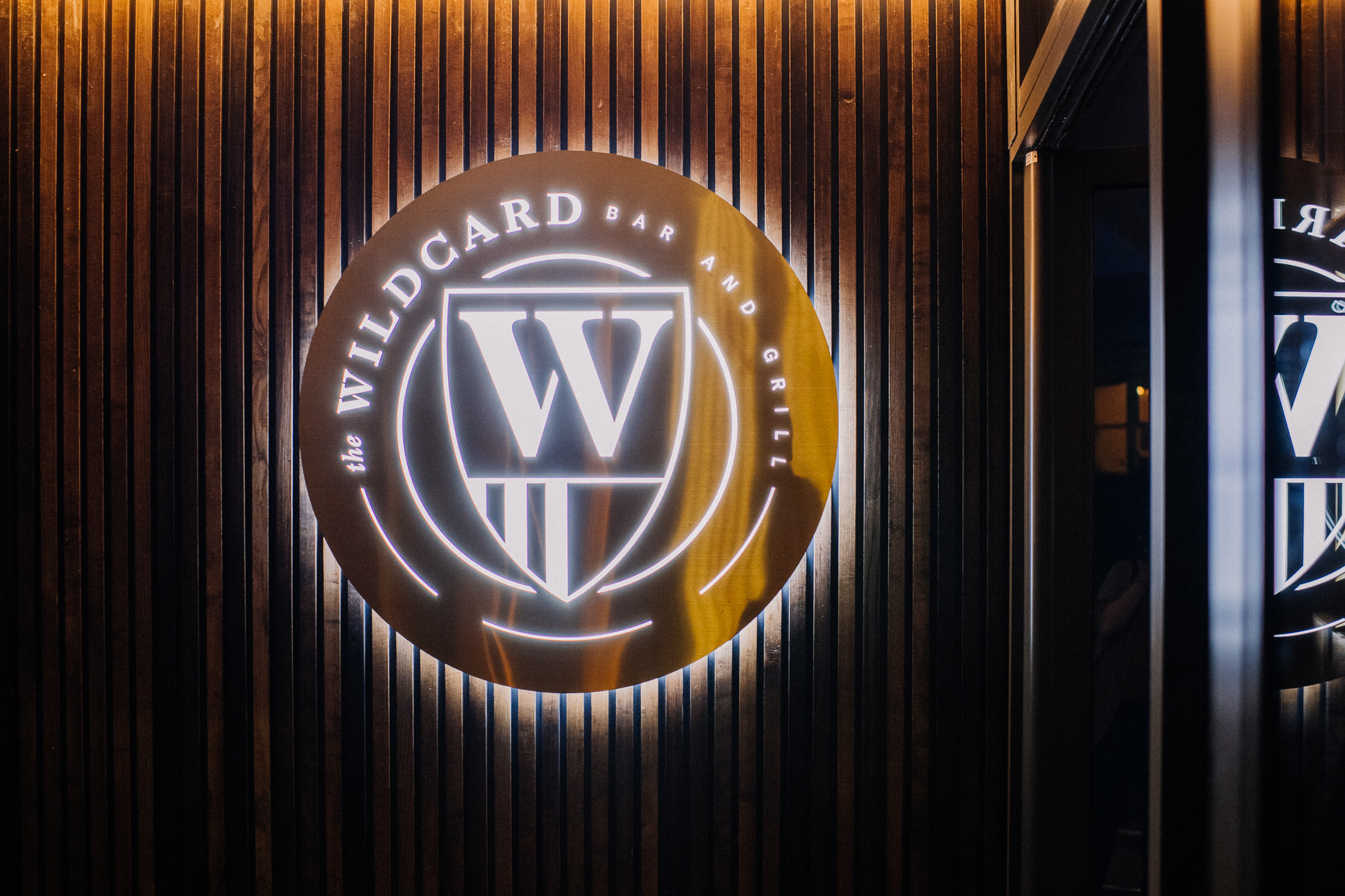The Wildcard Bar & Grill's logo, lit up, on a wall.