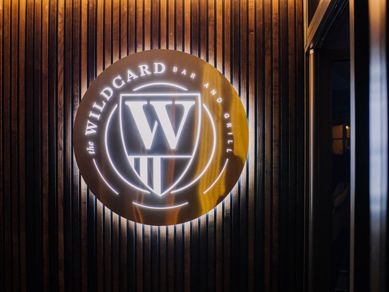 The Wildcard Bar & Grill's logo, lit up, on a wall.