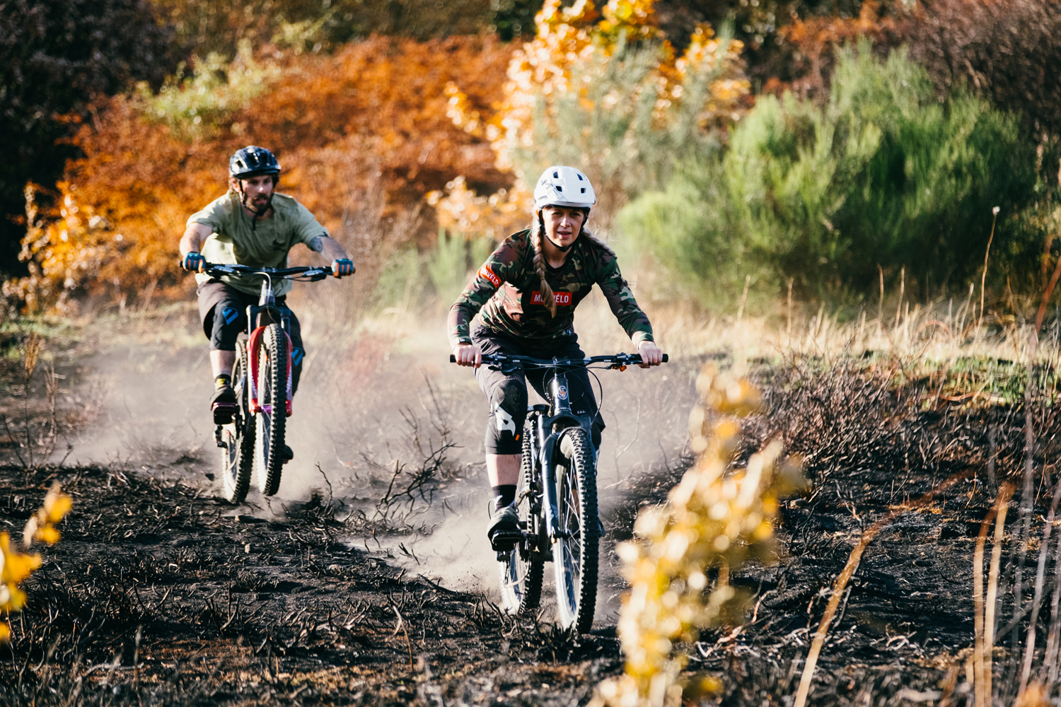 Two mountain bikers riding along a dirt track.