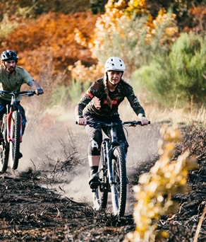 Two mountain bikers riding along a dirt track.