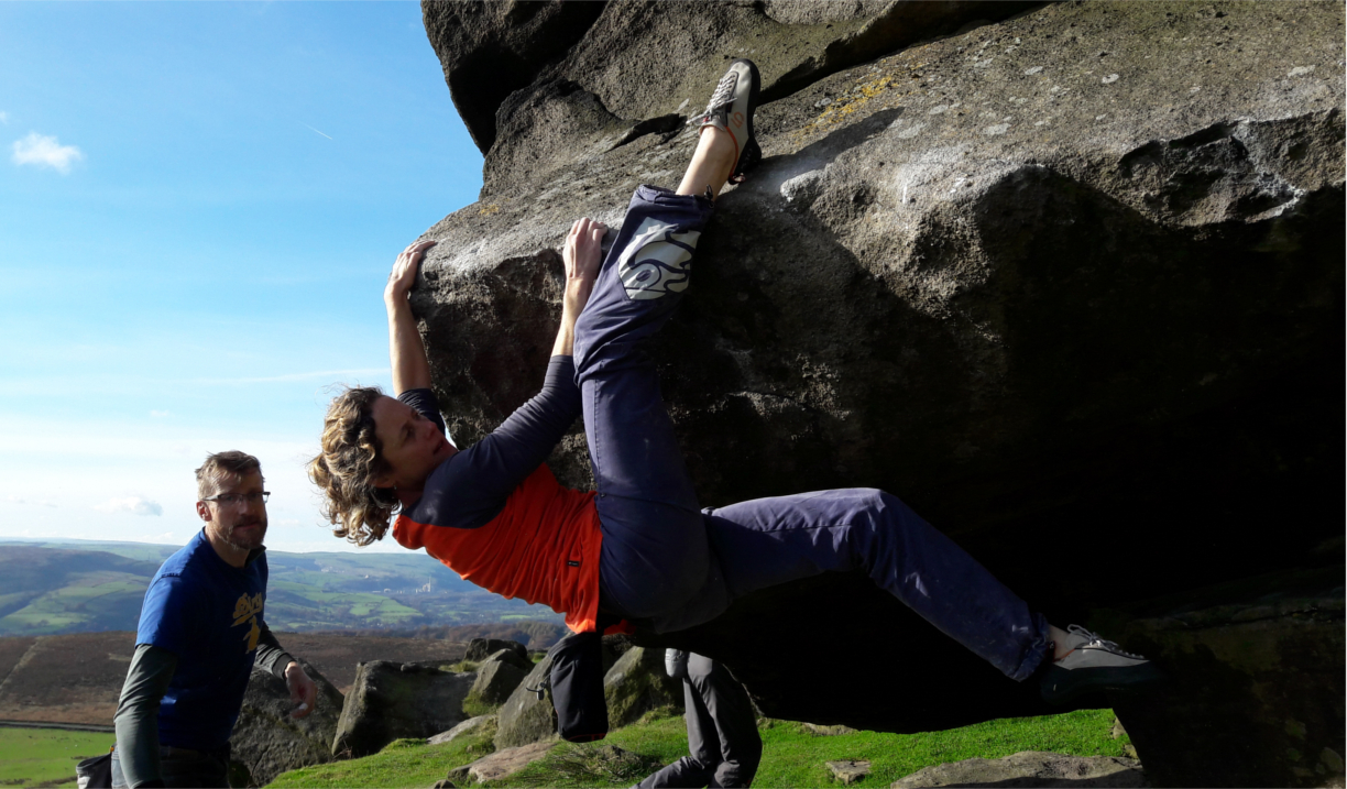 Two people climbing a boulder.