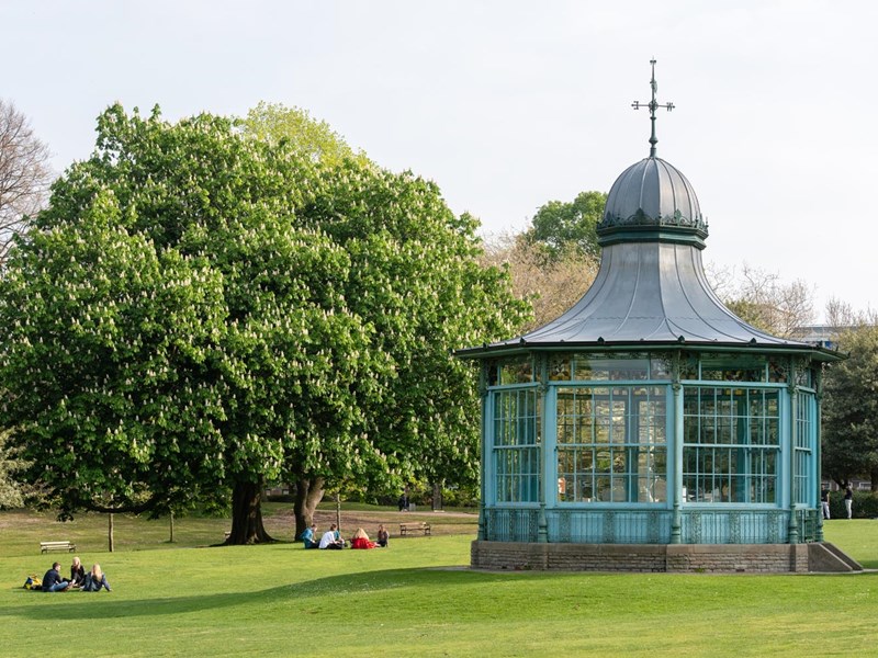 Weston Park bandstand with groups of people sat on the grass to the left.