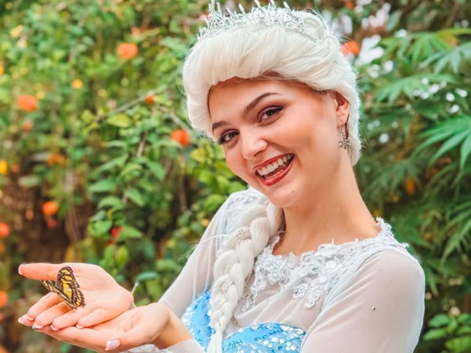 A woman dressed as a princess holding a butterfly.