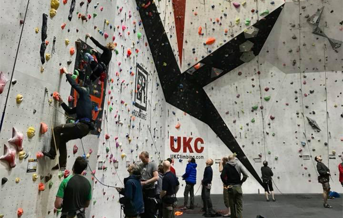 A big climbing wall at Awesome Walls Climbing Centre Sheffield. There are lots people climbing or waiting to climb.
