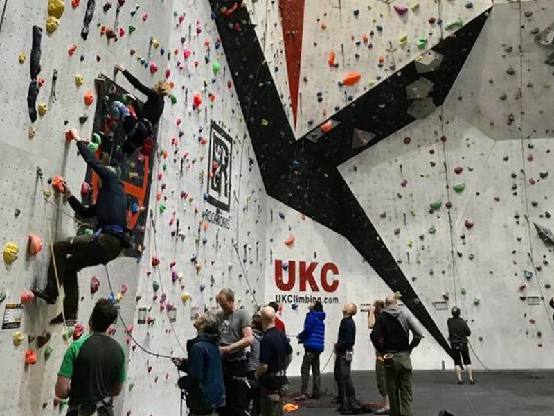 A big climbing wall at Awesome Walls Climbing Centre Sheffield. There are lots people climbing or waiting to climb.