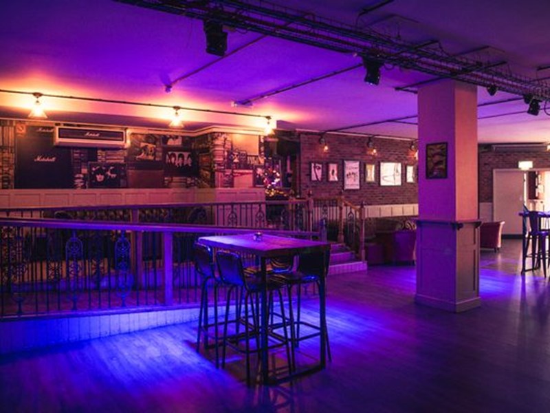 The dance floor and bar at Maida Vale, lit by purple lighting.
