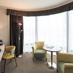 Spacious sitting area in a junior suite featuring a coffee table, armchair, and large windows with natural light