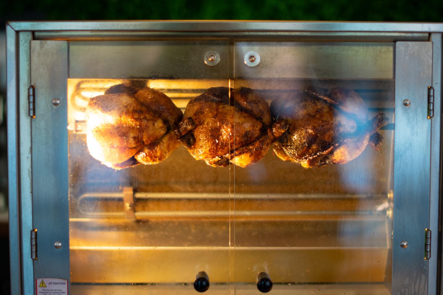 Three chickens in a rotisserie oven at Chop Shop Bar & Grill.