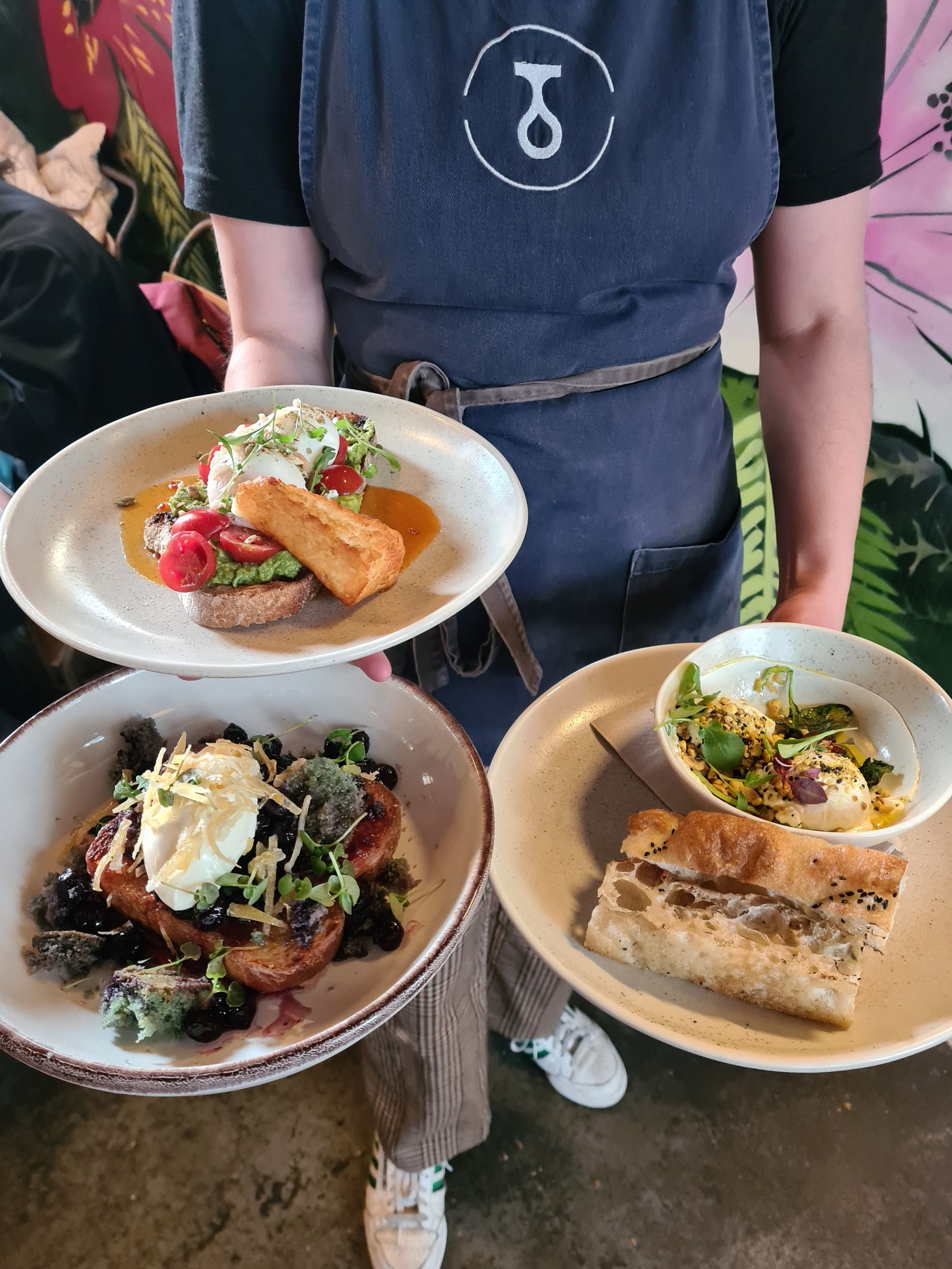 A member of Tamper Coffee staff carrying three plates of food to a table.