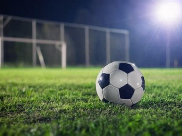 A black and white football sitting on a grass pitch.