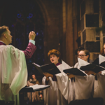 A man conducting a choir in a church.